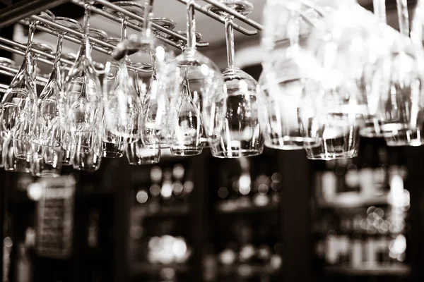 Empty glasses for wine above a bar rack — Stock Photo, Image