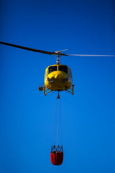 Požární záchranné těžký vrtulník s kbelík vody, jde na oheň. — Stock fotografie