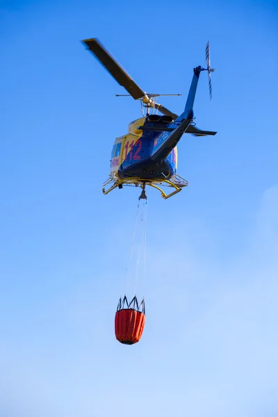Požární záchranné těžký vrtulník s kbelík vody, jde na oheň. — Stock fotografie