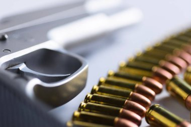 Doğal ışık arka planında bakır mermili yarı otomatik tabanca..