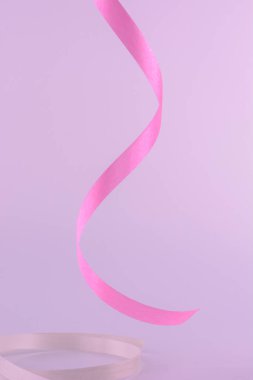 Curled ribbon on pink color background.