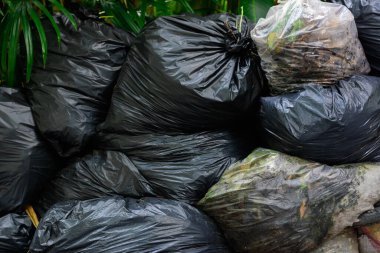 Doğal ışık arka planında biyolojik olarak çözünebilen plastik poşetlerle dolu bir çöp yığını..