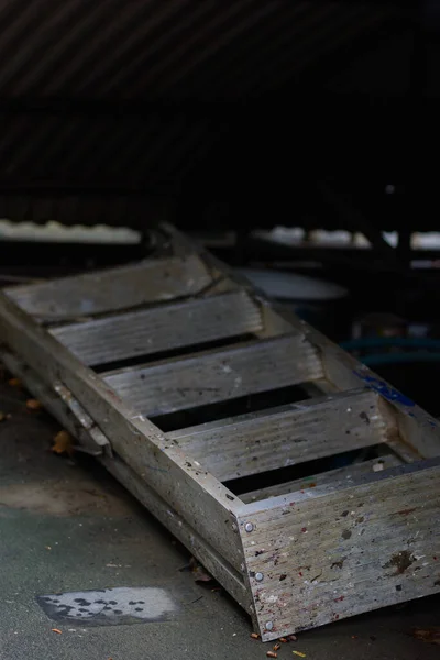 Unused dirty aluminum ladder on natural dark light background.