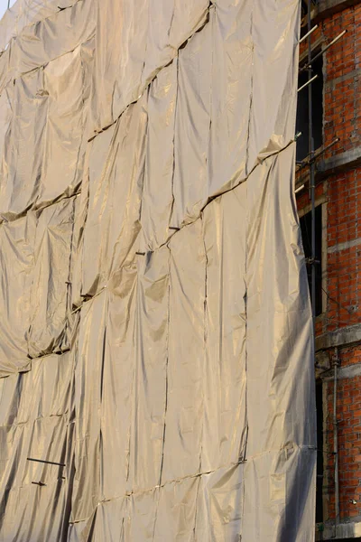 Canvas covers the building under construction to prevent hazard and pollution.