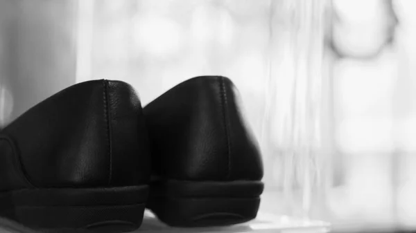 Black leather shoes on natural light background. Monochrome photography