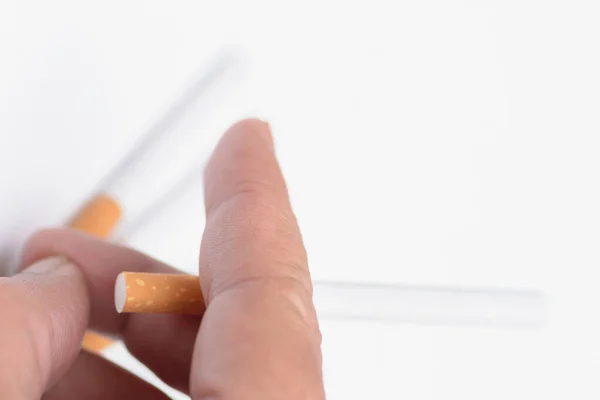 Human finger holding cigarette on natural white background.