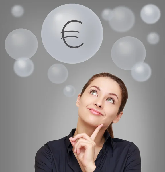 Thinking smiling woman looking up on euro sign in bubble on grey — Stock Photo, Image