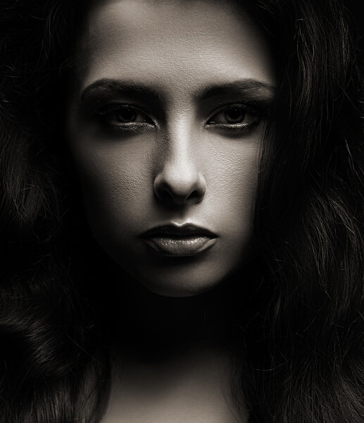 Closeup portrait of beautiful woman face on dark shadows background