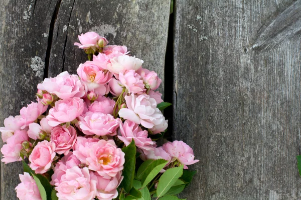 Pequeñas rosas rosadas del jardín en la superficie de madera — Foto de Stock