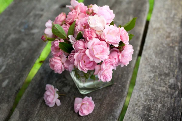 Маленькие розовые розы на деревянной поверхности — стоковое фото