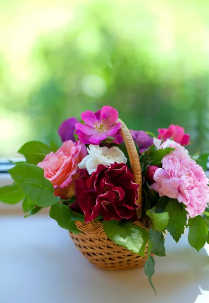 Kleurrijke rozen in mand op vensterbank — Stockfoto