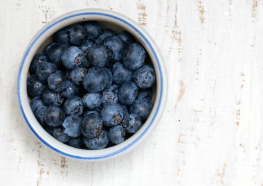 ahşap masa üzerinde taze yaban mersini ile kase