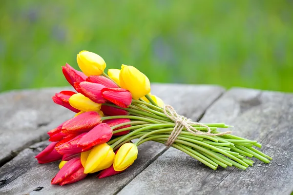 Kötött sárga és piros tulipán fa felületen — Stock Fotó