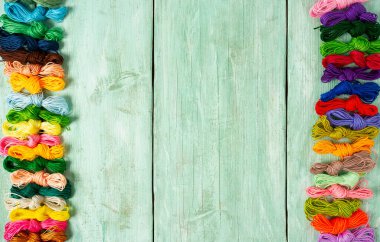 Ahşap turkuaz arka planda nakış işlemek için çok renkli iplikler.