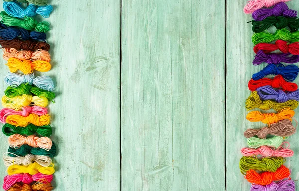 Ahşap turkuaz arka planda nakış işlemek için çok renkli iplikler.