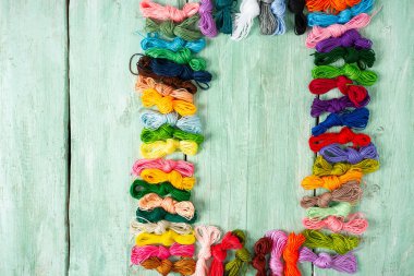 Ahşap turkuaz arka planda nakış işlemek için çok renkli iplikler.