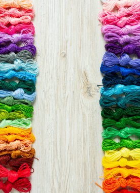 Ahşap turkuaz arka planda nakış işlemek için çok renkli iplikler.