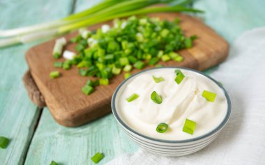 sour cream with sliced onion on wooden surface, top view