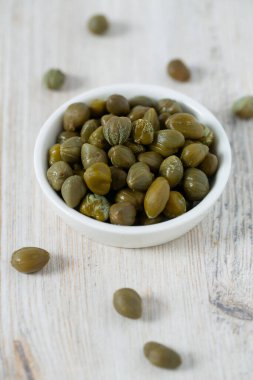 Beyaz ahşap yüzeyde turşulu kapari. Gurme yemekleri..