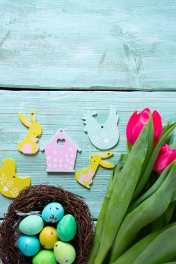 Kahverengi ahşap yüzeyde renkli laleler ve Paskalya yumurtaları. Paskalya yumurtası kartpostalı. Metnin için boş yer. Üst görünüm.