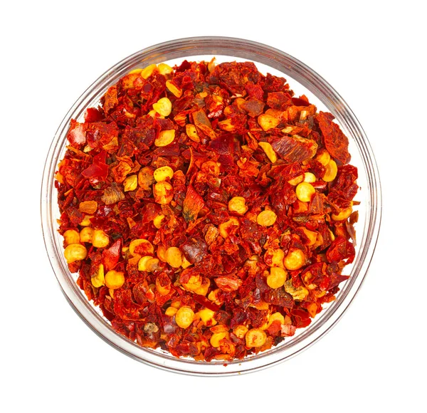 Beyaz arka planda izole edilmiş cam bir kasede kurutulmuş acı biber.