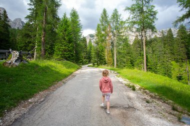 Şirin kız dağ yamacında yürüyor. Çocuklarla İtalyan Dolomitleri 'nde seyahat etmek.. 