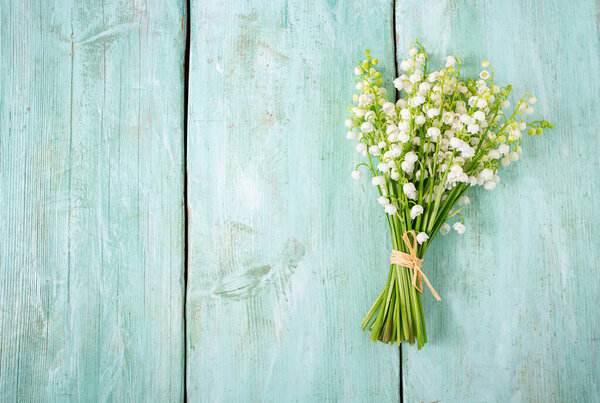 Beautiful flowers of lily of the valley, top view and empty space for your text. Nature background on wooden surface.