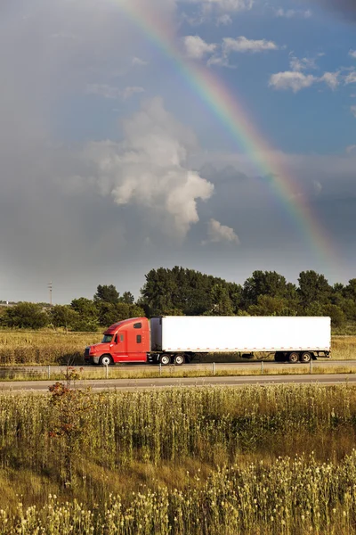Semi caminhão dirigindo sob o arco-íris — Fotografia de Stock
