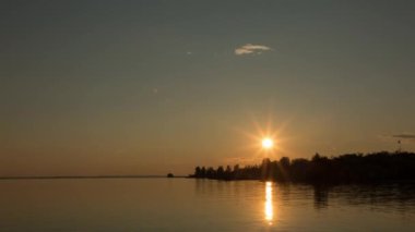 Sakin bir nehrin kıyısında güzel bir gün batımı, zaman akıp gidiyor.