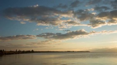 Bulutlu bir nehrin üzerinde gün doğumu, zaman akıp gidiyor.