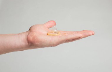 Erkeklerin elinde güvenli seks prezervatifi, doğum kontrol hapı.