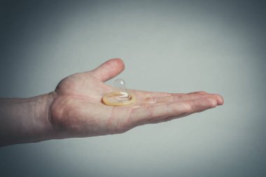 Erkeklerin elinde güvenli seks prezervatifi, doğum kontrol hapı.