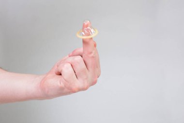 Erkeklerin elinde güvenli seks prezervatifi, doğum kontrol hapı.