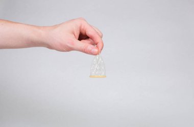 Erkeklerin elinde güvenli seks prezervatifi, doğum kontrol hapı.