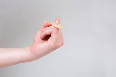 Erkeklerin elinde güvenli seks prezervatifi, doğum kontrol hapı.