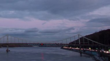 Kiev 'de gün batımında nehir boyunca büyük bir köprü, yağmurlu bir hava.