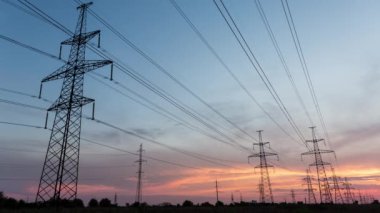 Turuncu bir günbatımının arka planına karşı büyük elektrik direkleri, zaman aşımı, 4K