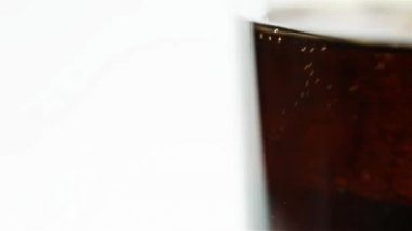 Bardaktaki soda beyaz arka planda buz küpleriyle döner.