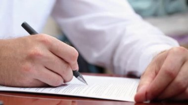 Bir ofis çalışanı belgeleri dolma kalemle doldurur. Belgelerle birlikte ofiste çalışıyor. Ofis çalışanı