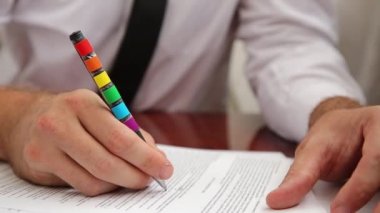 Ofisteki adam çalışıyor, kağıt işlerini gökkuşağı LGBT 'li kalemle hallediyor.