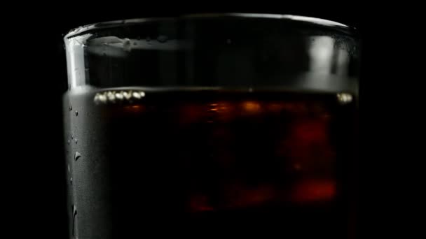 黒い背景の中央に干渉するウイスキーとソーダと氷のキューブのガラス — ストック動画