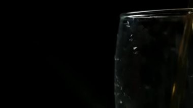 Bira, sağdan köpükle siyah zemin üzerinde büyük bir bardağa dökülüyor.