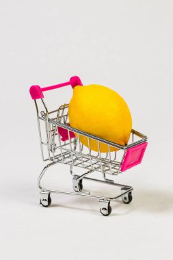 Beyaz bir arka planda market arabasında limon