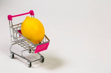 Beyaz bir arka planda market arabasında limon