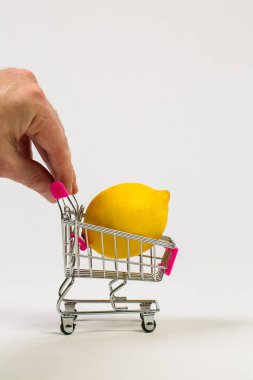 Beyaz bir arka planda market arabasında limon