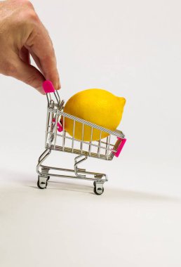 Beyaz bir arka planda market arabasında limon