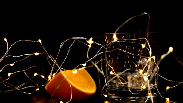 Кусок Апельсина Стакан Льдом Который Наливают Сок Новогодней Гирляндой — стоковое видео