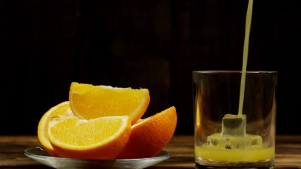 果汁倒入装有冰块的杯子里 几片橙子放在盘子里 — 图库视频影像