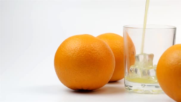 Sinaasappelsap Wordt Een Glas Gegoten Drie Sinaasappels Een Witte Achtergrond — Stockvideo