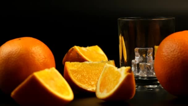 Kawałki Pomarańczy Całych Pomarańczy Oraz Soku Nalewane Szklanki Lodem Czarnym — Wideo stockowe